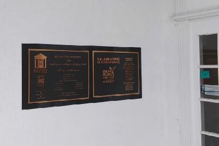 Two bronze plaques on a white wall next to a white door with glass panes.