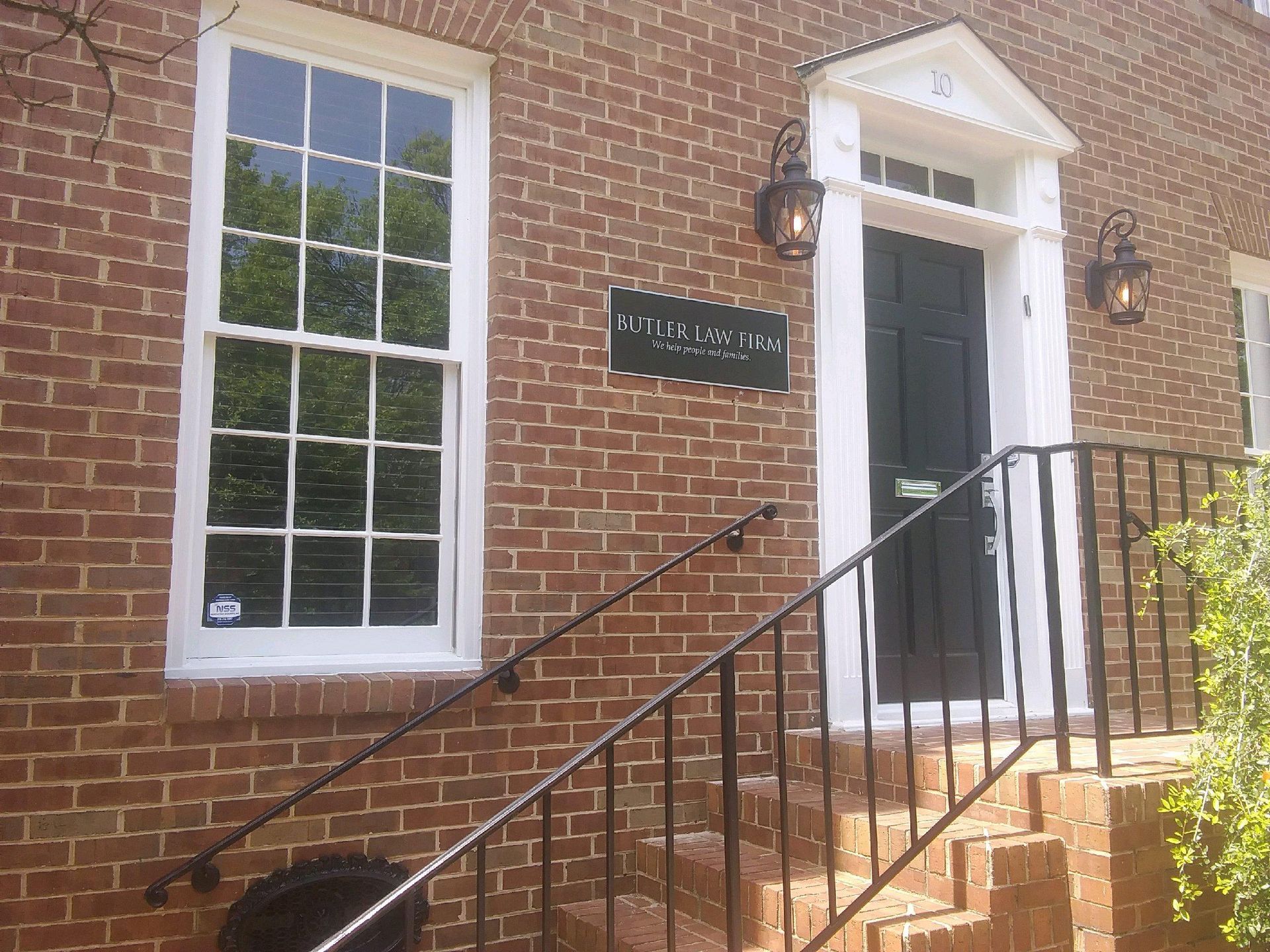 Red brick building with black door, white trim, and a window. Sign above the door.