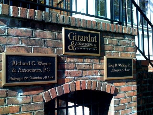 Brick wall with three office signs: Girardot & Associates, Richard C. Wayne, and Greg A. Walling, Attorneys at Law.