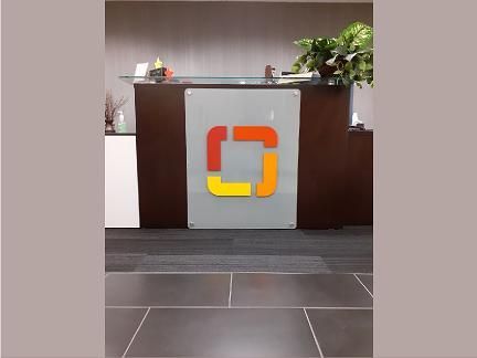 Reception desk with a logo of a square made of orange, yellow and red rectangles.