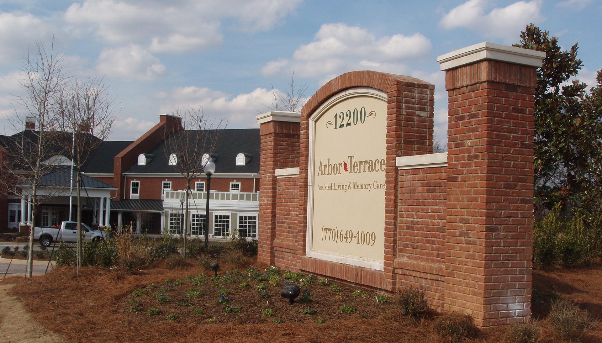 Sign for Arbor Terrace with a brick building in the background.