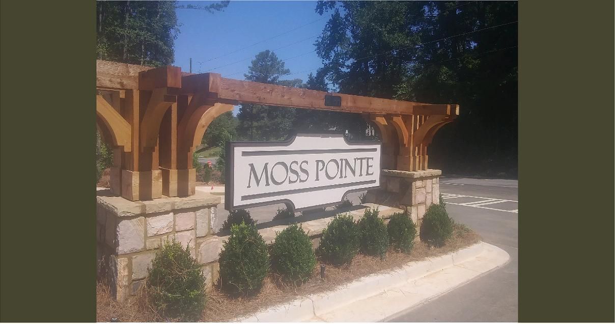Entrance sign for Moss Pointe community.  Wooden archway over a stone sign with the community name.