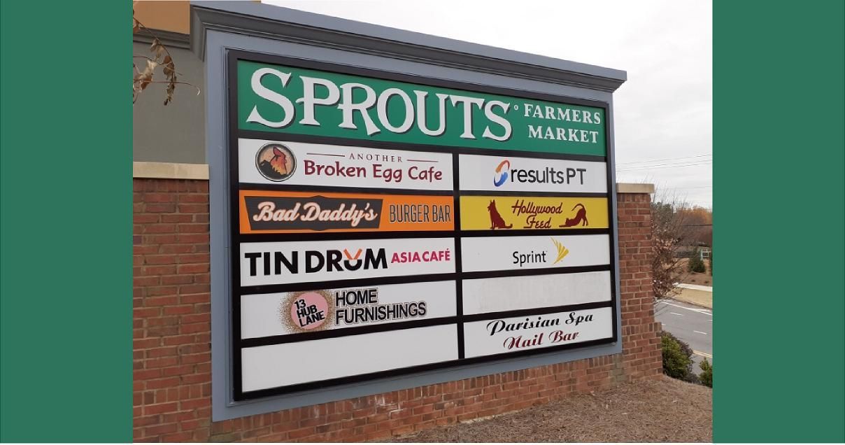 Sign for a shopping center with tenants including Sprouts, Broken Egg Cafe, and Tin Drum.