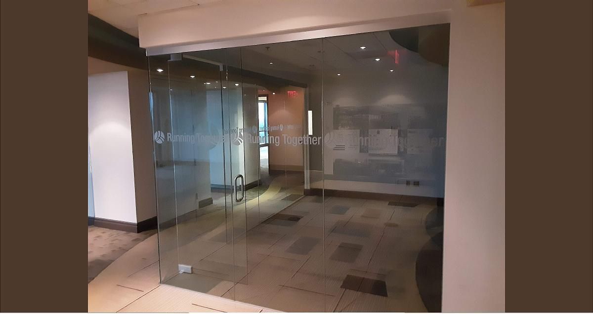 Glass doors leading to an office space. Etched frosted text is visible on the doors.