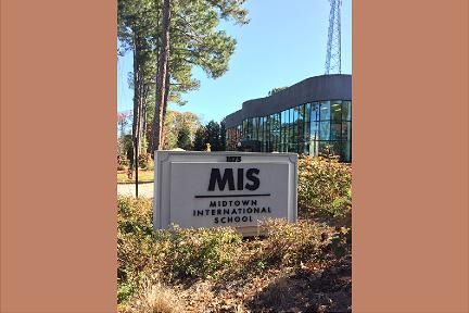 Sign for Midtown International School with building in background.