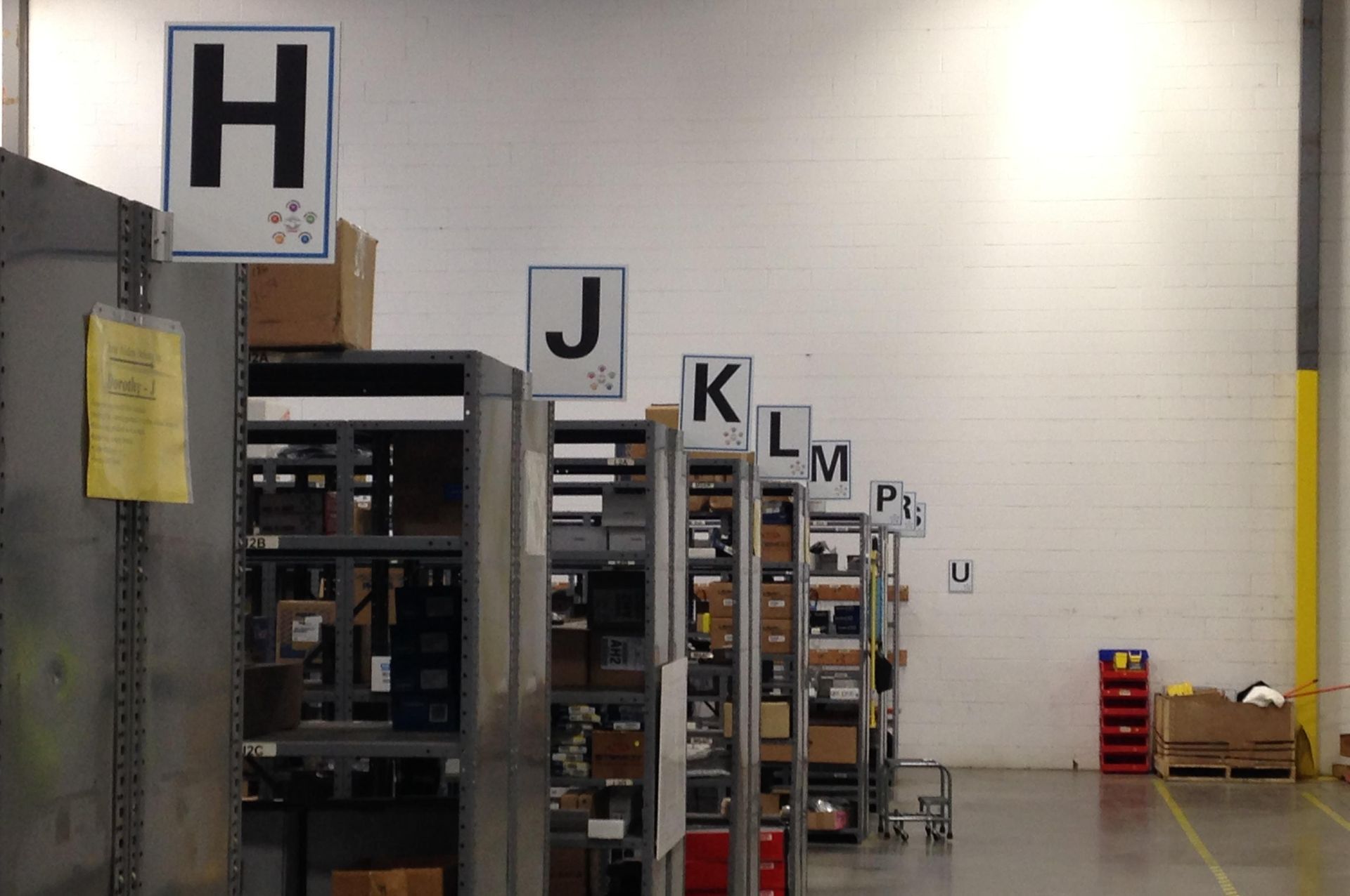 Warehouse shelving labeled with letters, boxes, and items on shelves.