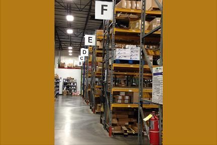 Warehouse shelves labeled with letters, full of boxes and items.
