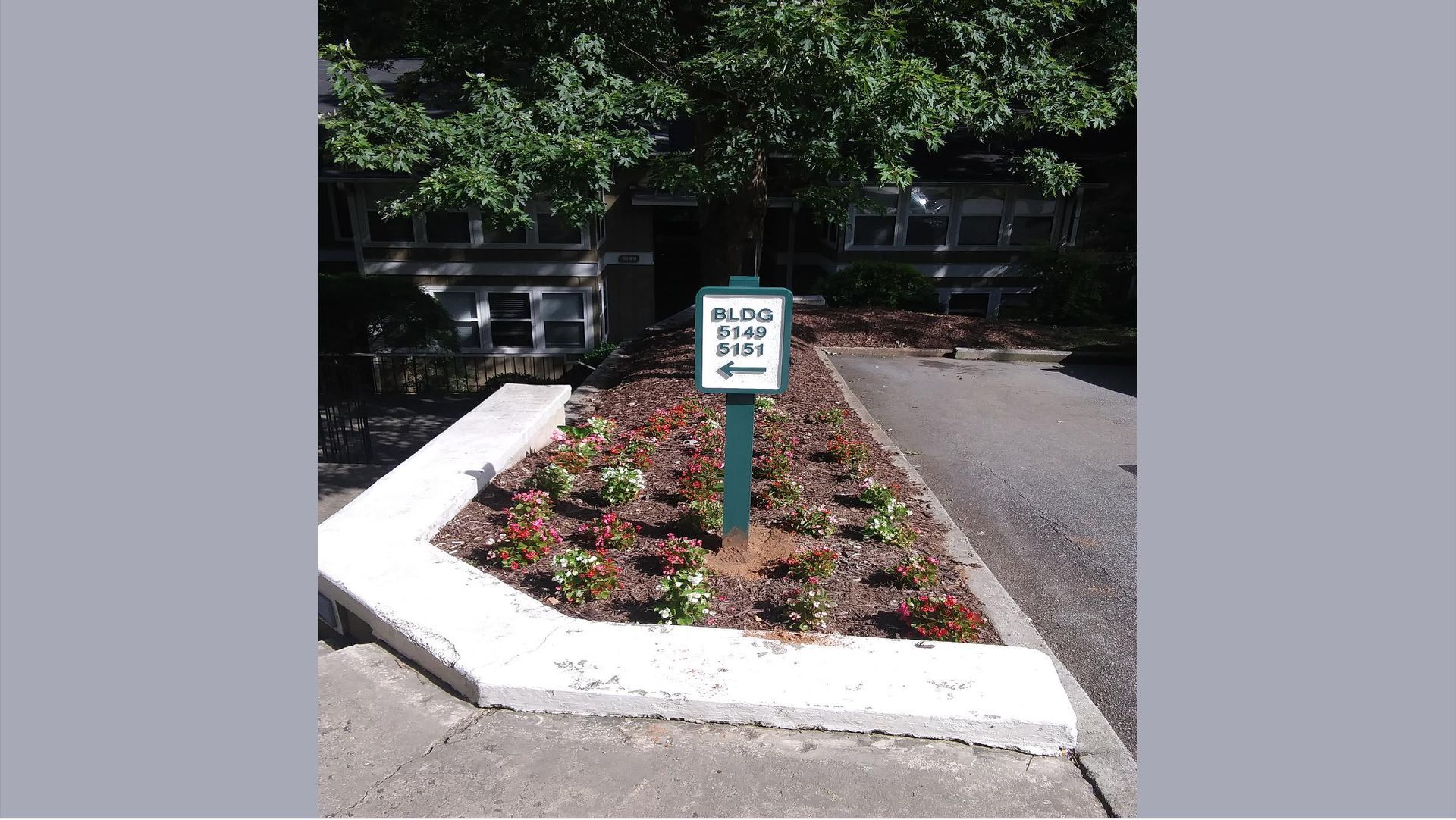 Flower bed with a green sign, likely indicating a place.