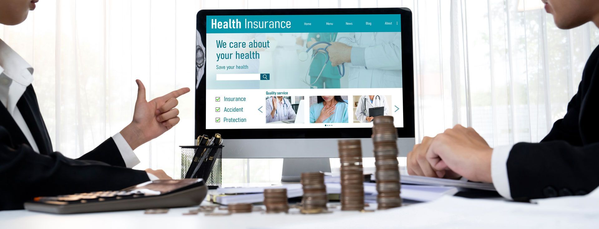 Business meeting with two people discussing a computer screen showing a website and stacked coins on the desk