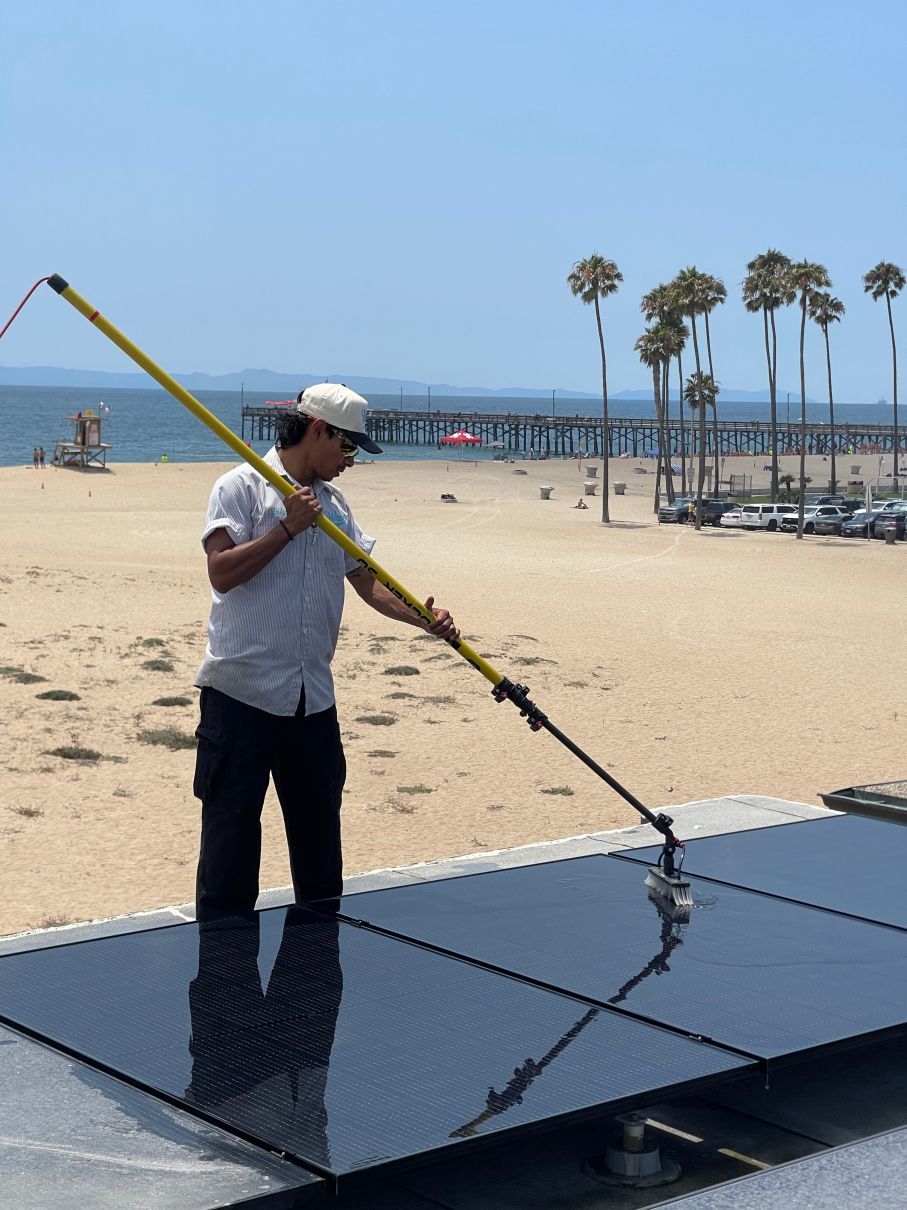 Person cleaning solar panels on a sunny beach near the ocean