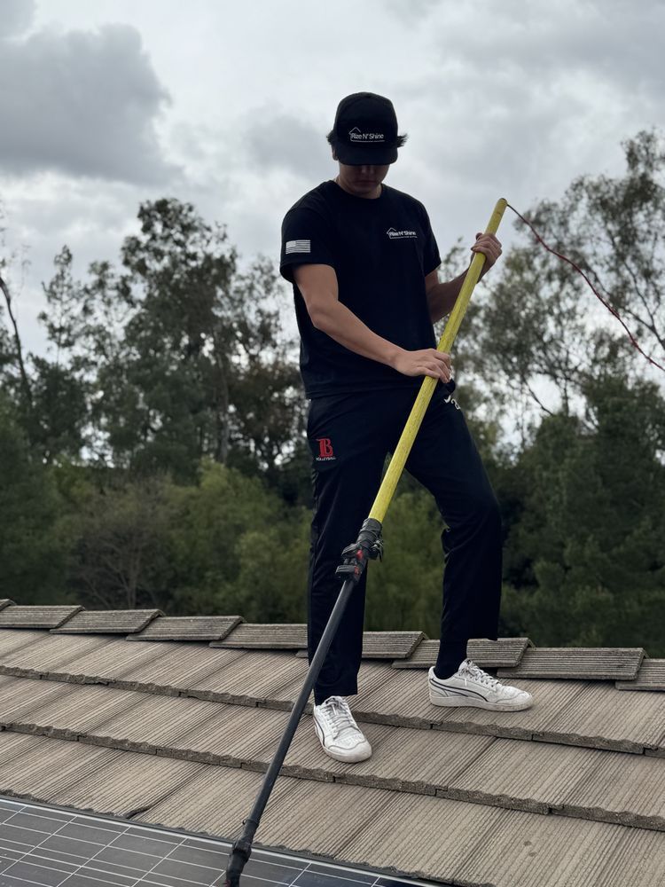Person on a rooftop installing a yellow safety line, wearing black clothing and white sneakers.