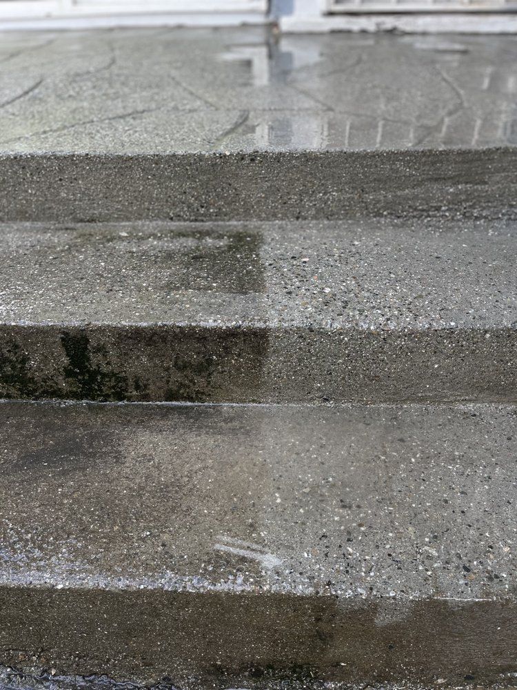 Wet concrete steps outdoors with a blurred building reflection in the background