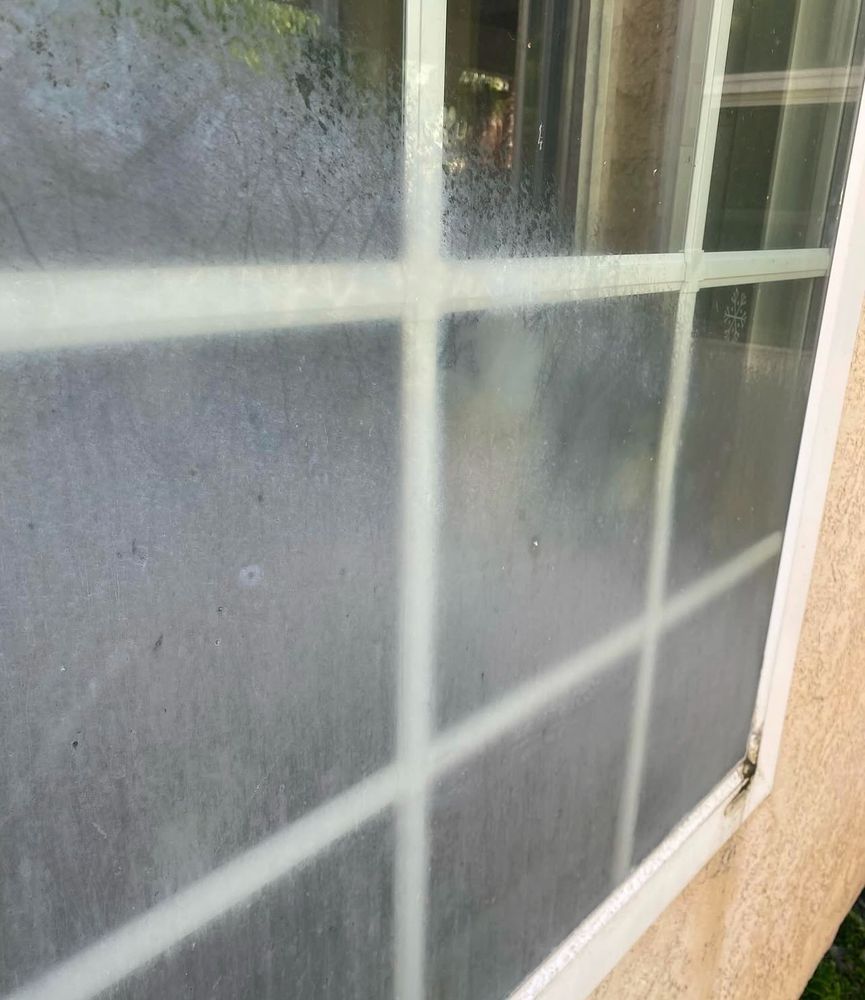 Fogged window with white grid panes and a beige wall outside