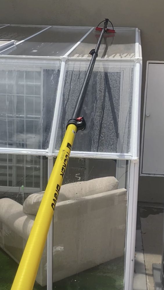 Yellow pole reaching toward a white screened enclosure with a beige chair inside, in a room.