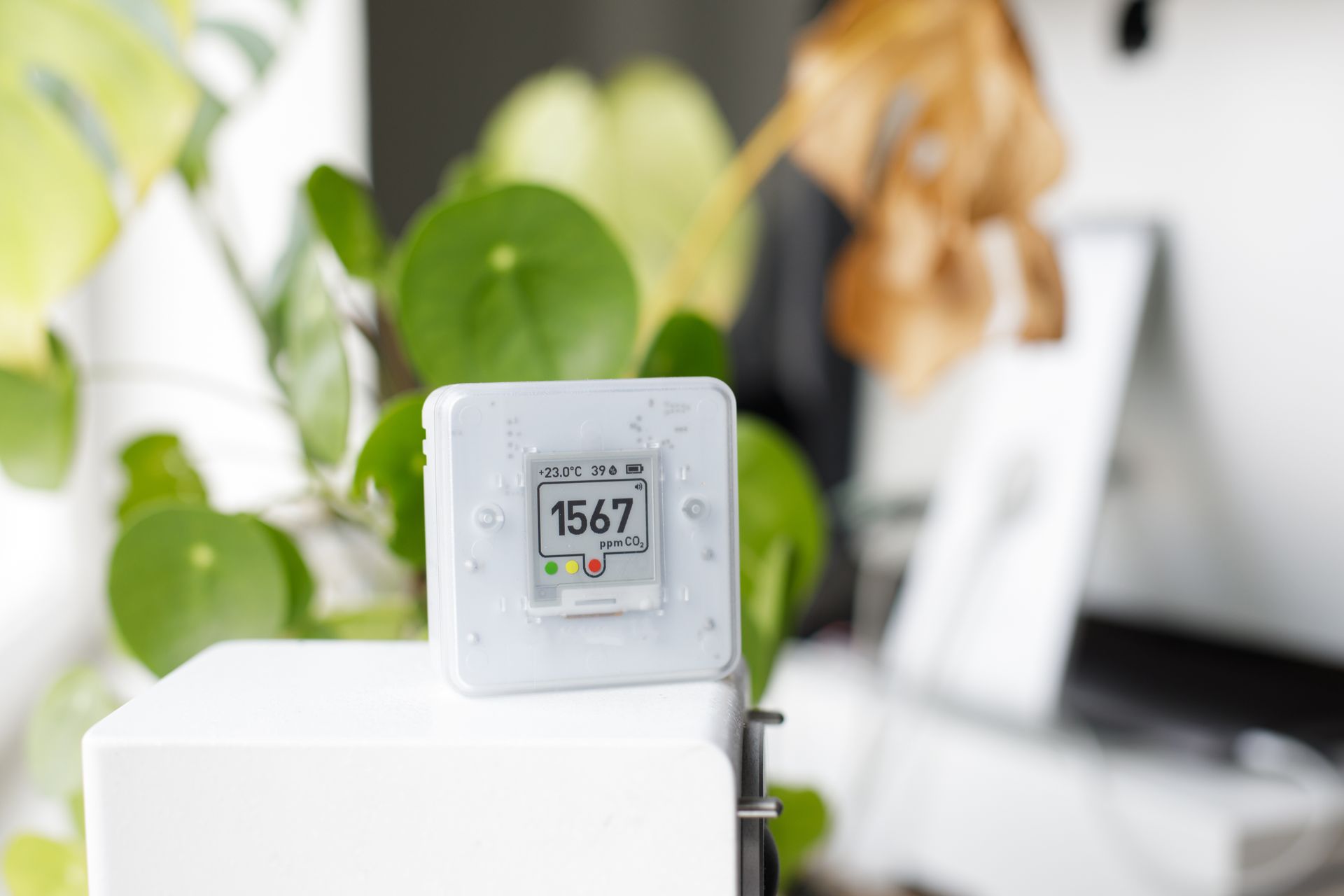 A white thermostat is sitting on top of a white box.