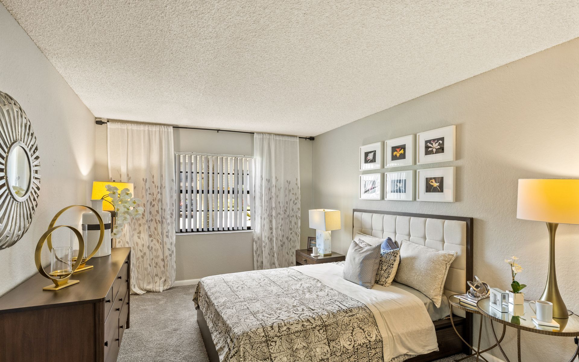 Bright bedroom with a bed, nightstands, lamps, window, and patterned accent wall decor.