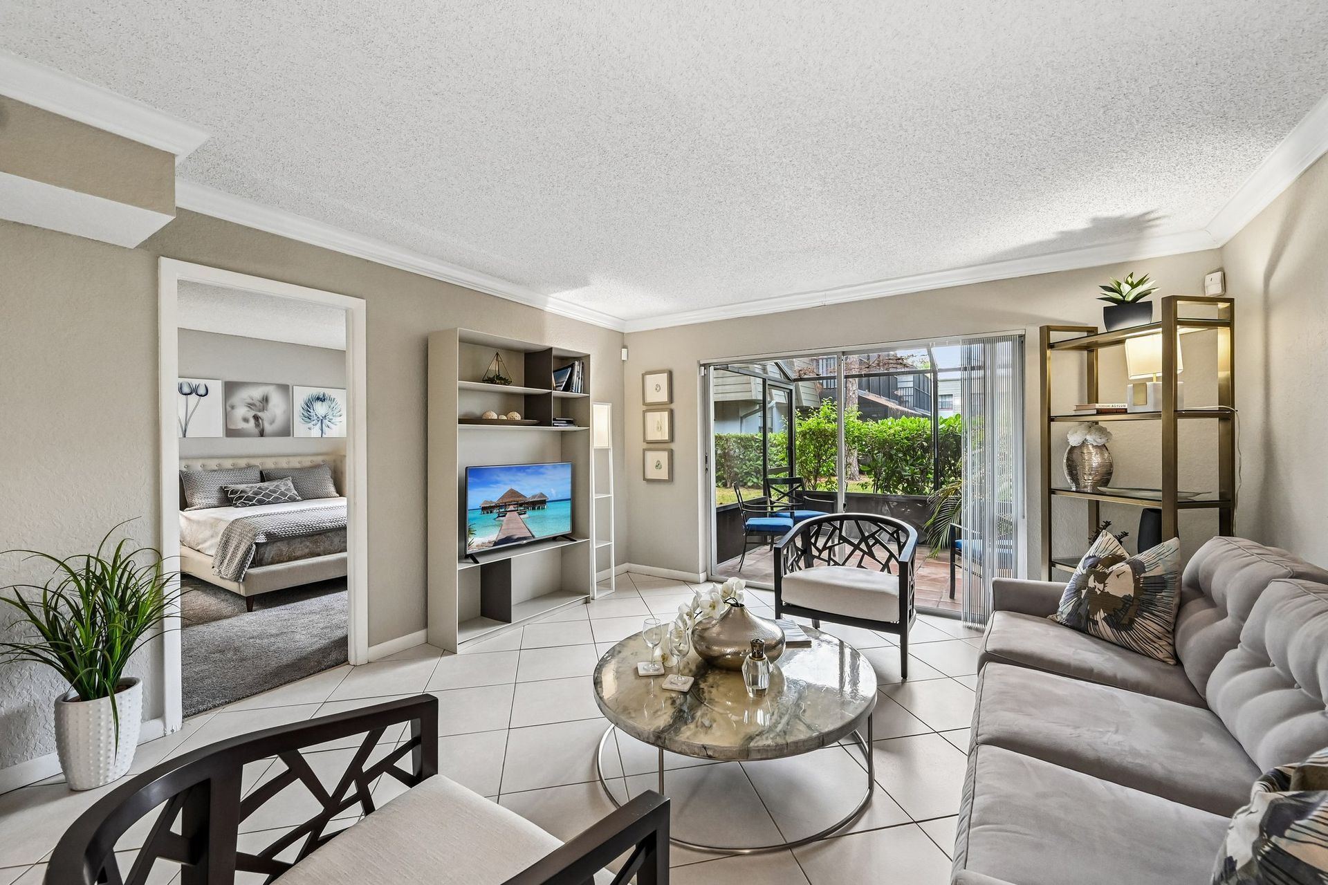 Bright modern living room with gray sofa, TV, coffee table, and sliding doors to a patio.