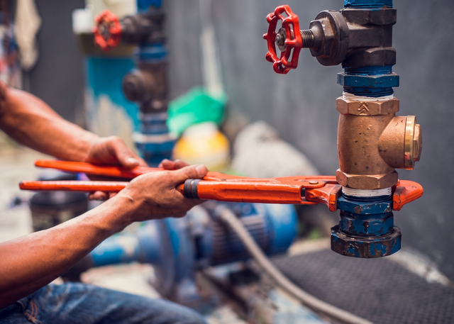 Industrial mechanical room with blue, red, and yellow piping, pumps, and control equipment