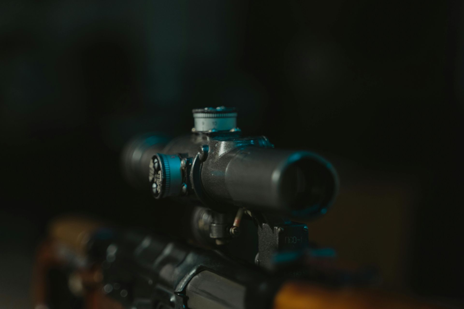 Close-up of a rifle scope mounted on a wooden rifle, set against a dark background.
