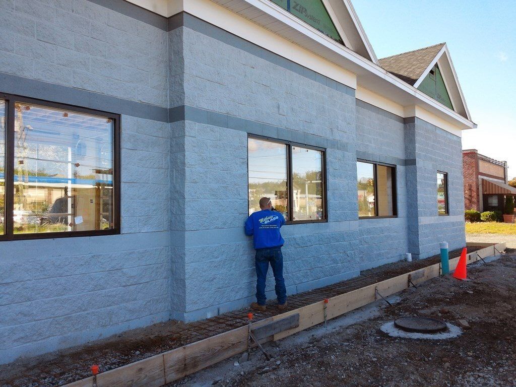 A man in a blue shirt is standing on the side of a building