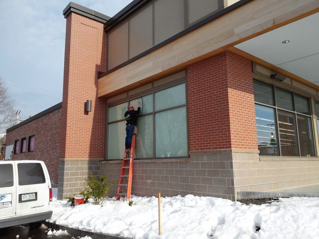 A man on a ladder is cleaning the windows of a building