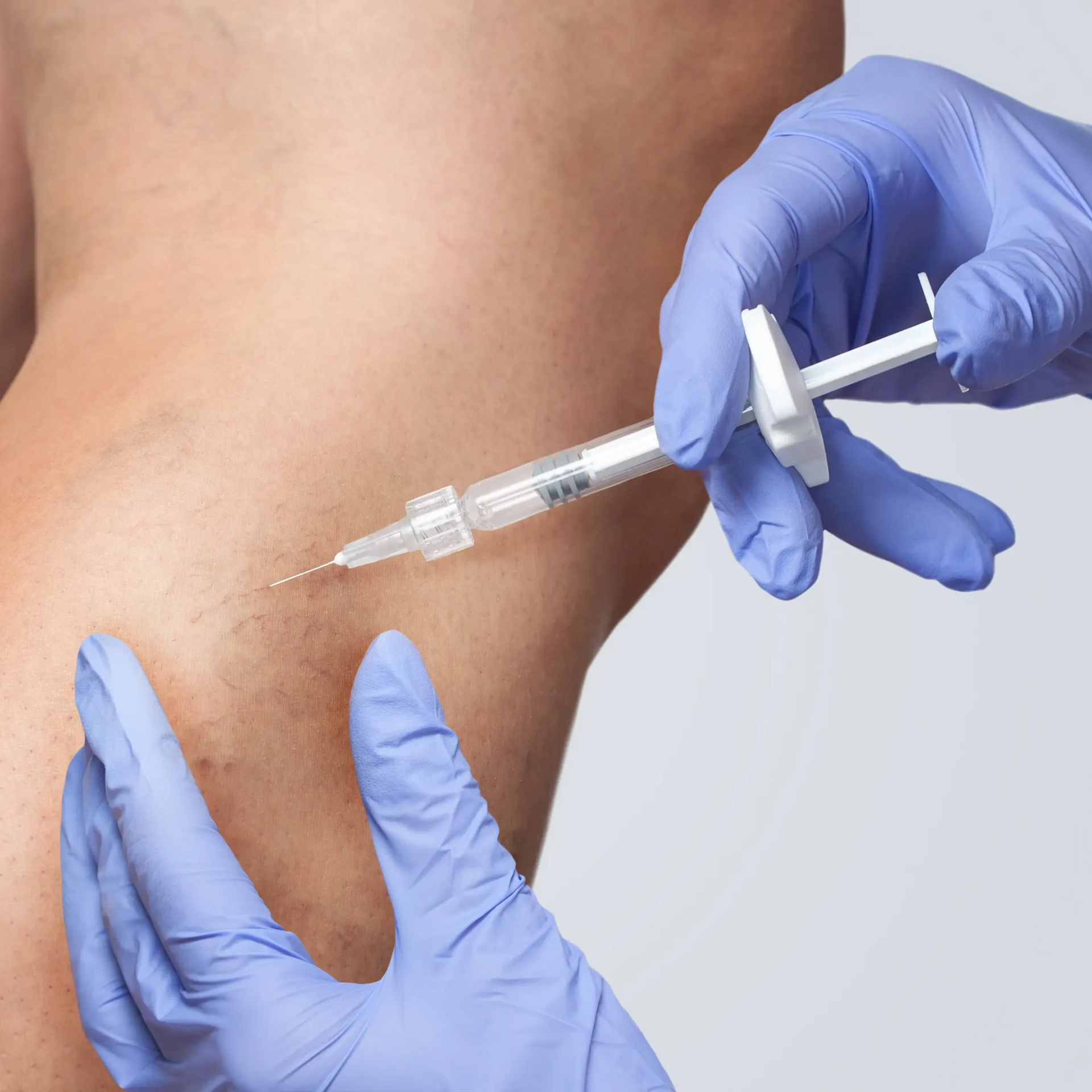 Gloved hands injecting medicine into a person’s upper arm with a syringe