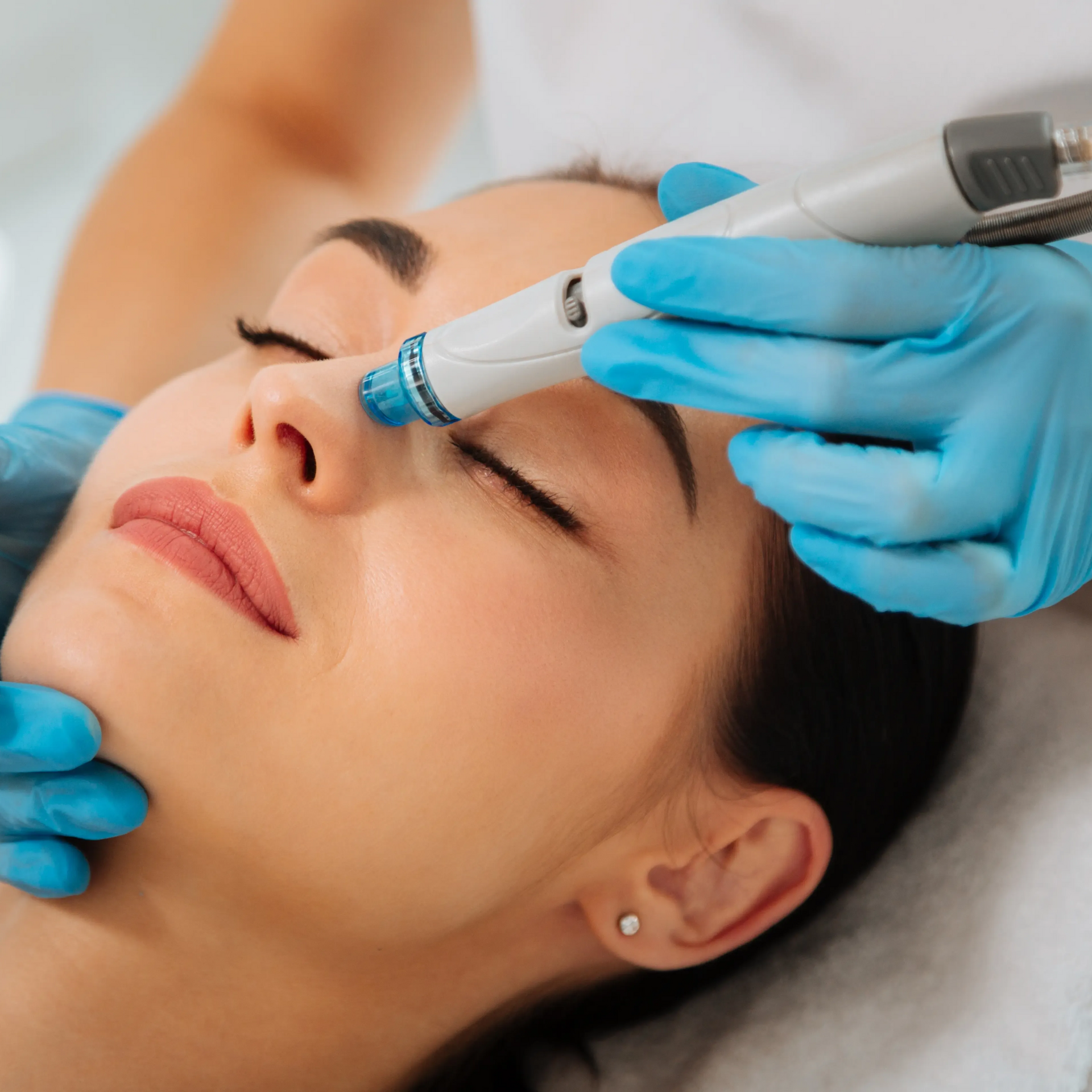 Cosmetic facial treatment with a gloved practitioner using a device on a woman's forehead