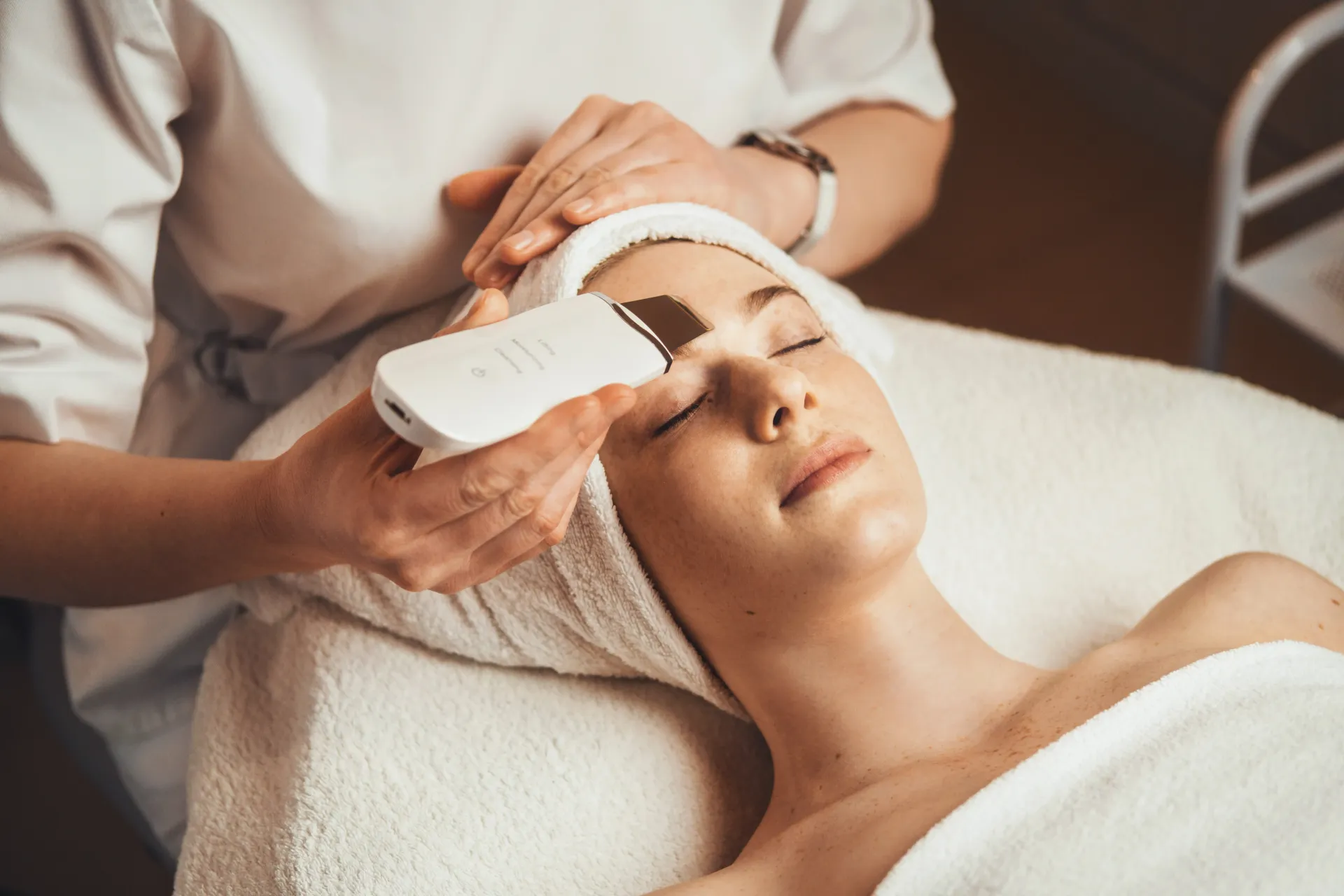 A facial treatment being applied to a woman lying on a spa bed with a headband.