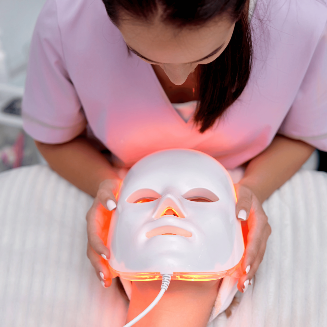 Woman receiving a glowing LED facial mask treatment in a spa setting
