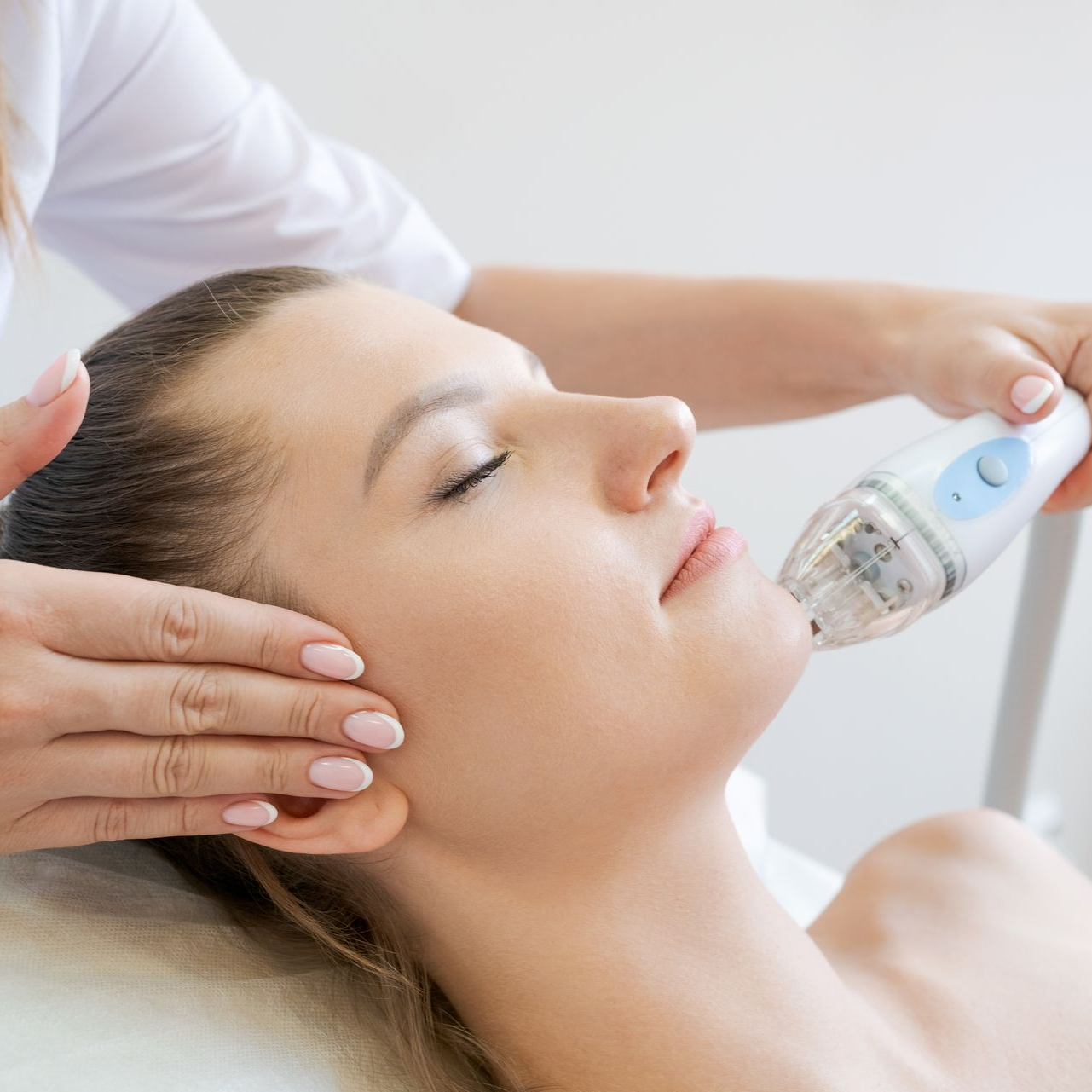 Facial treatment with handheld device on reclining client in a spa setting