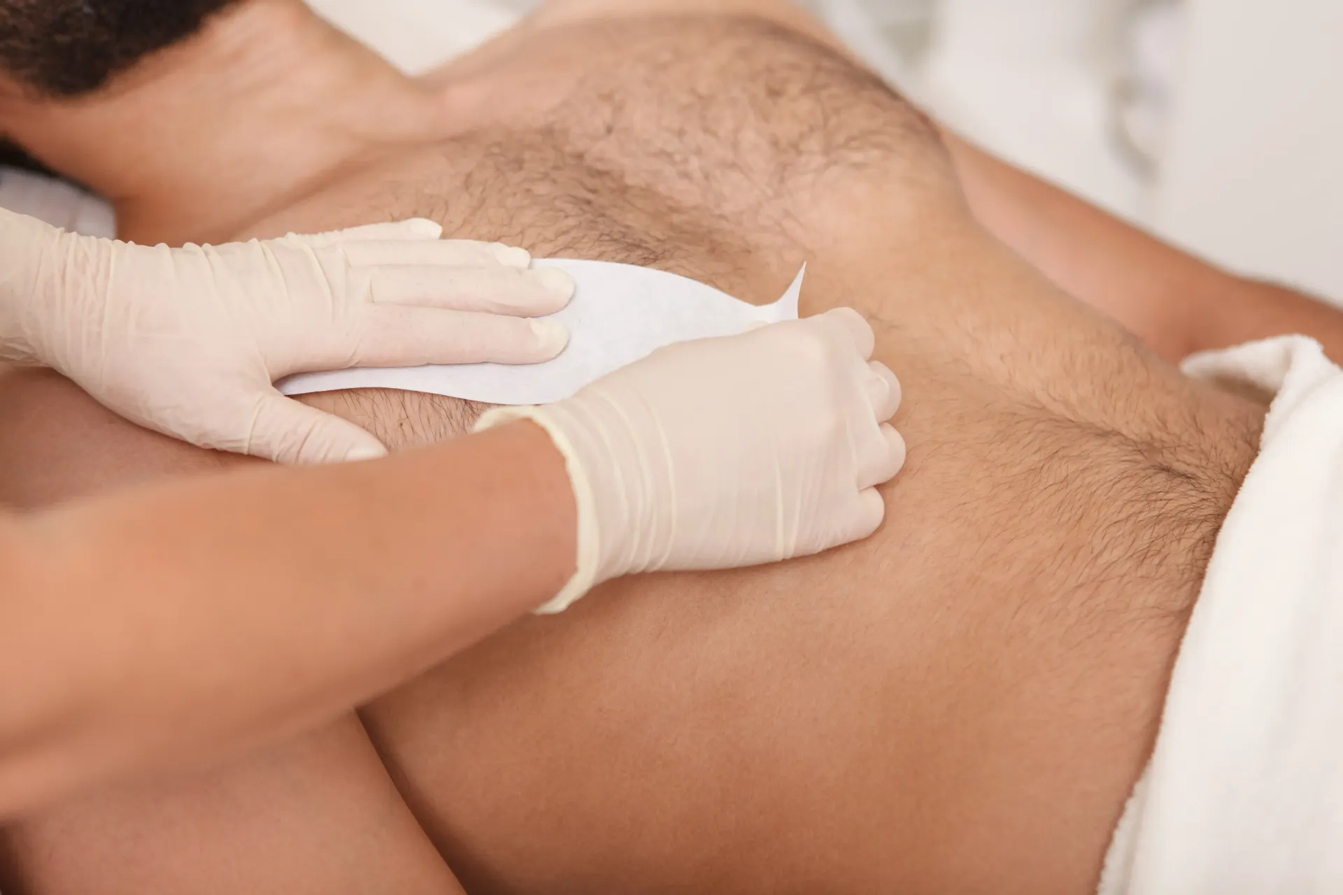 Gloved hands performing a back massage on a person lying face down on a towel