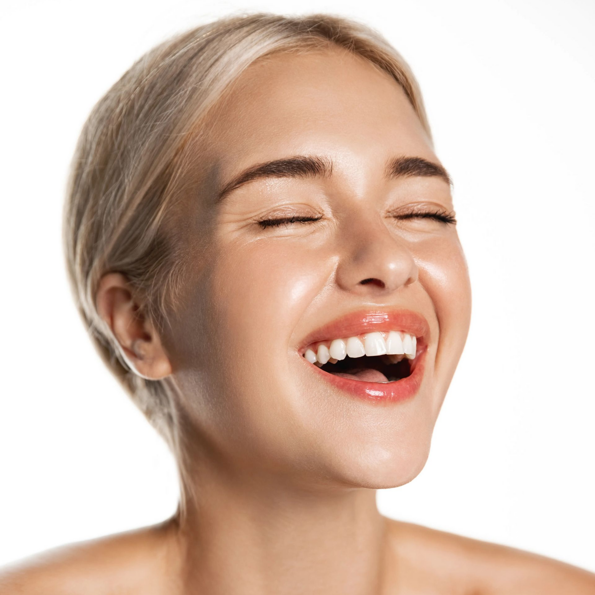 Close-up of a smiling person with closed eyes, blond hair, and bright red lipstick against a white background