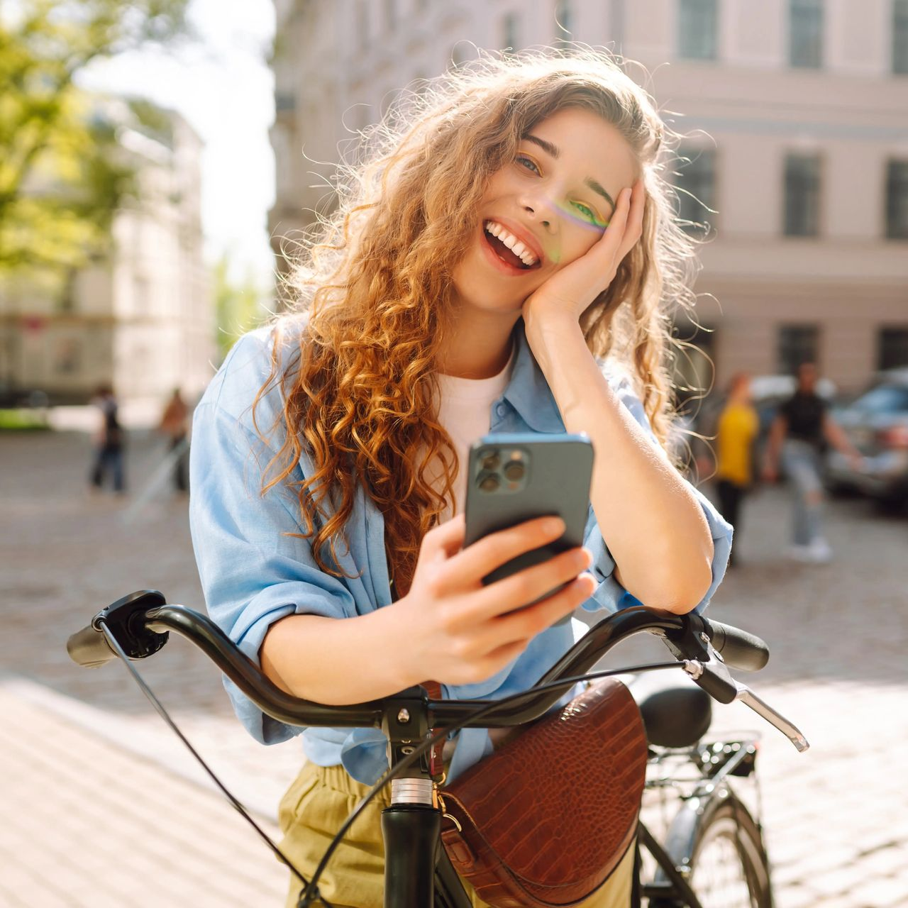 Smiling woman on a bicycle taking a selfie on a sunny city street