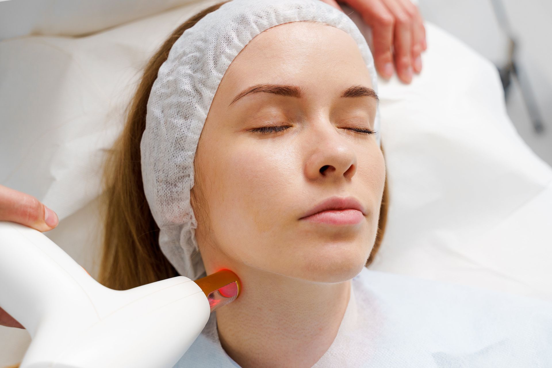 Woman receiving a facial treatment with a handheld device in a spa setting