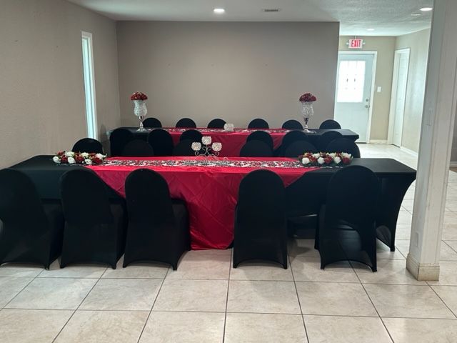A long table with a red table cloth and black chairs