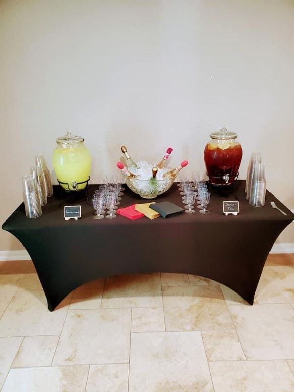 A table with a black table cloth and drink dispensers on it.