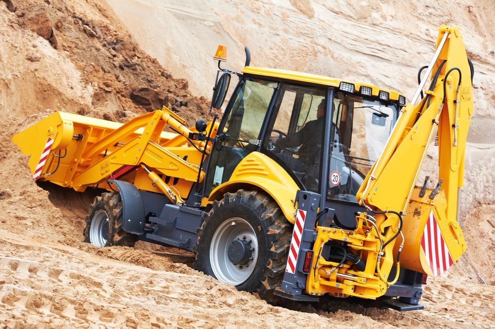 Yellow Backhoe Digging in Sand — Far North Plumbing in Mourilyan, QLD