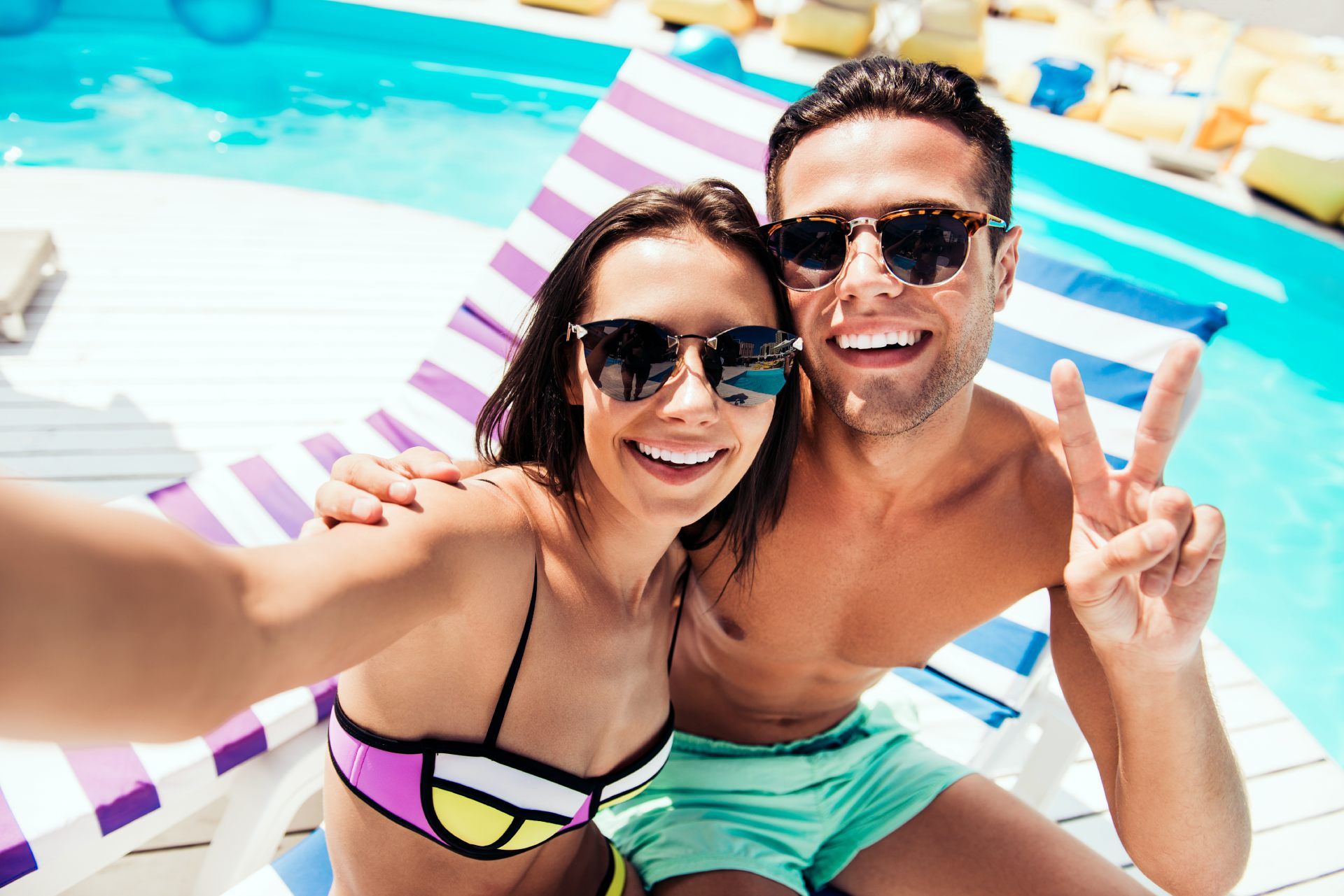 Un uomo e una donna si scattano un selfie accanto a una piscina.
