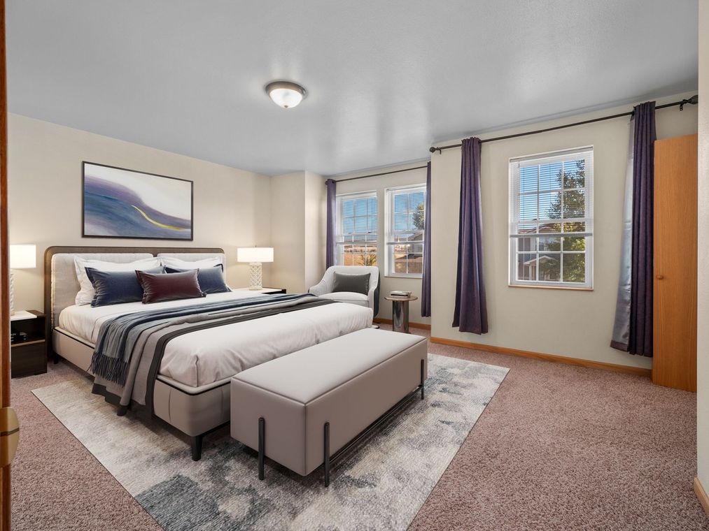 Bright bedroom with a bed, bench, windows, and neutral decor on a carpeted floor.