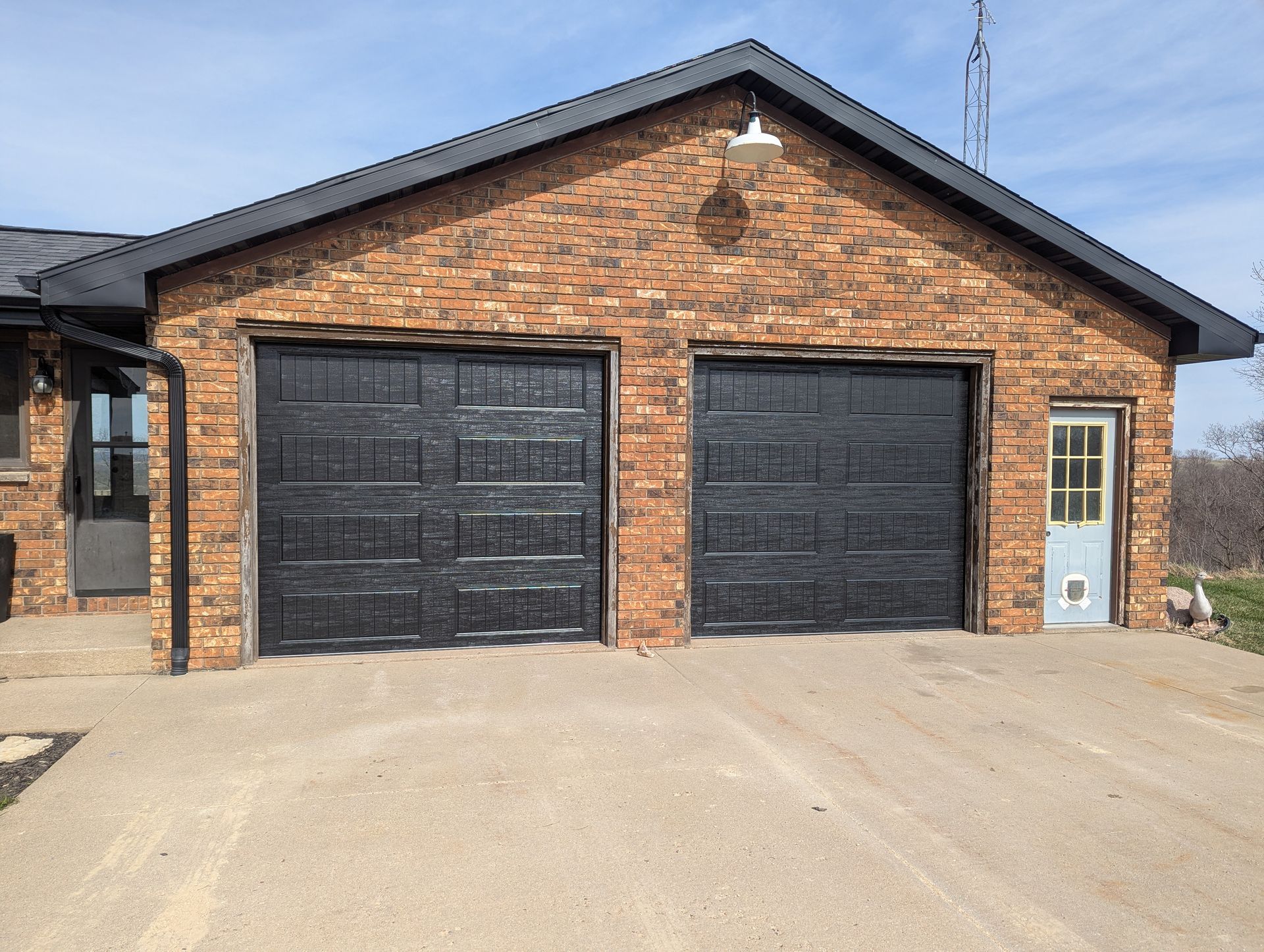 Brick house garage with two black doors and a small side entry door