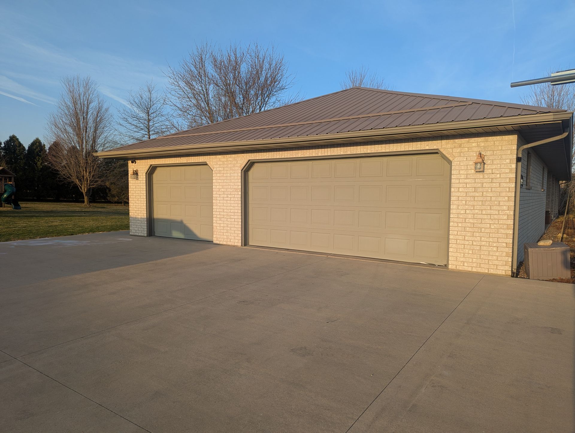 Two-car beige garage with closed doors on a sunny residential driveway