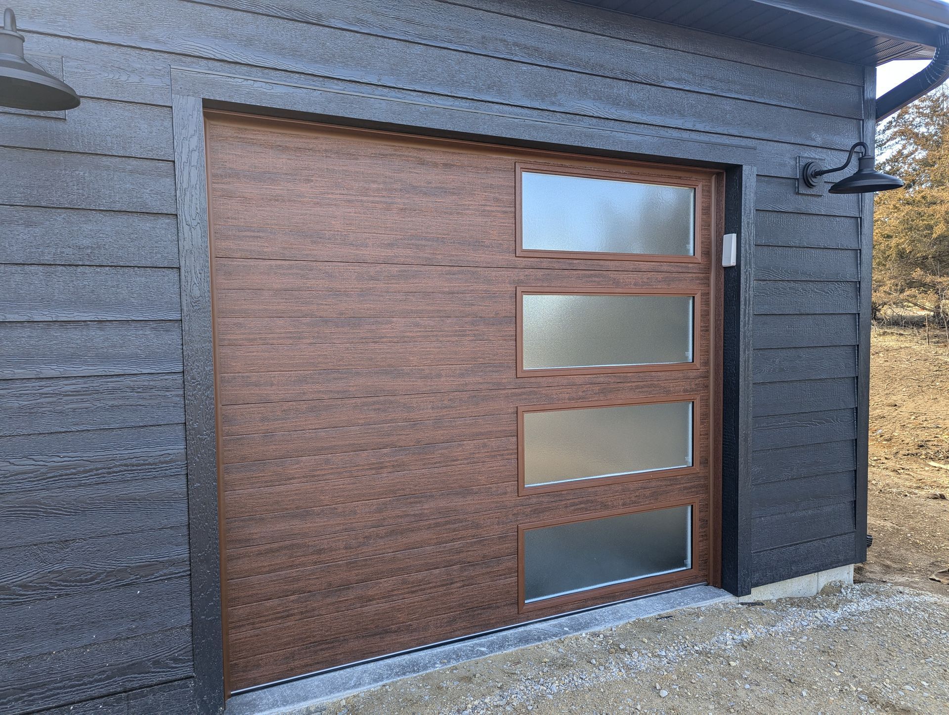 Modern wooden garage door with three frosted glass panels set in a dark exterior wall