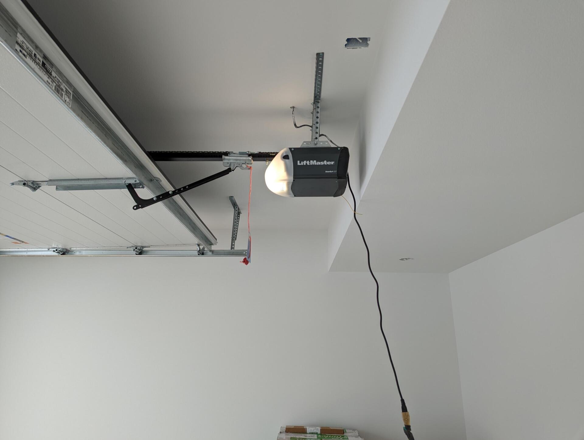 Open garage with ceiling-mounted opener and hanging cord against white walls