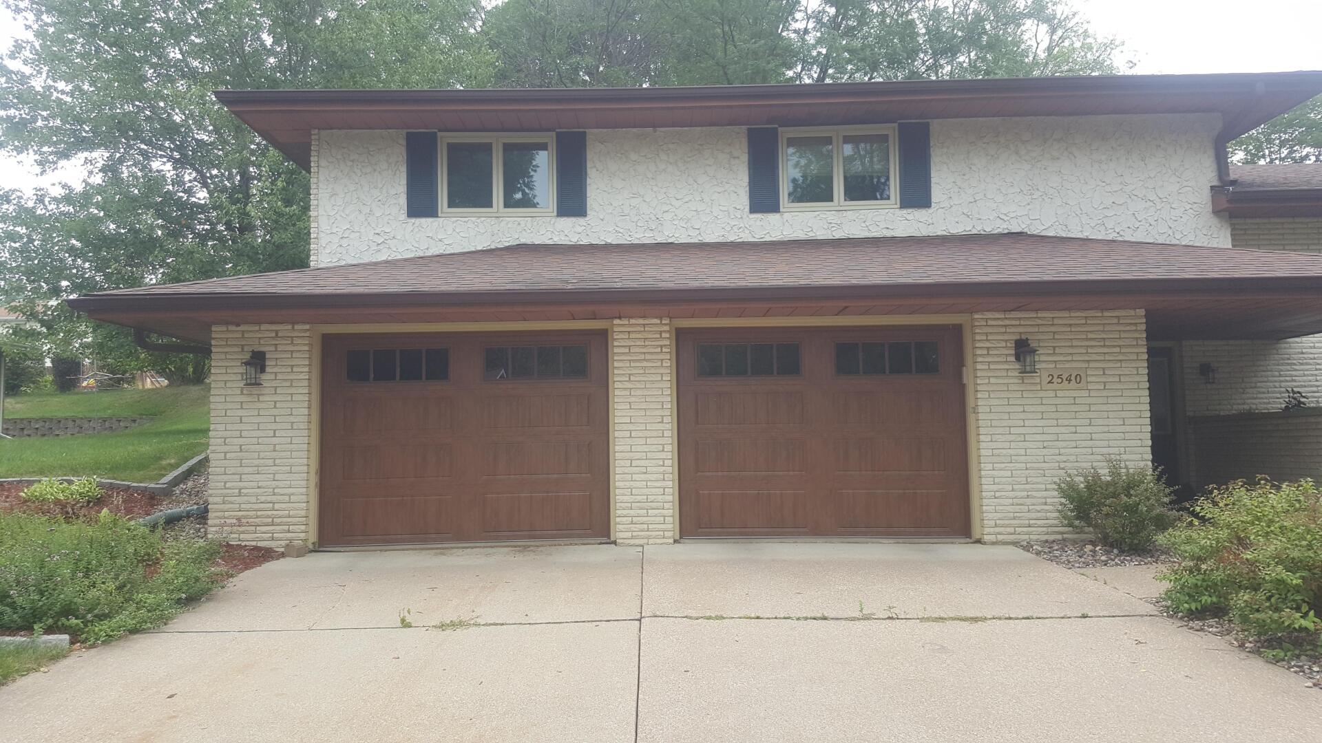 Suburban two-story house with a double wooden garage and concrete driveway.