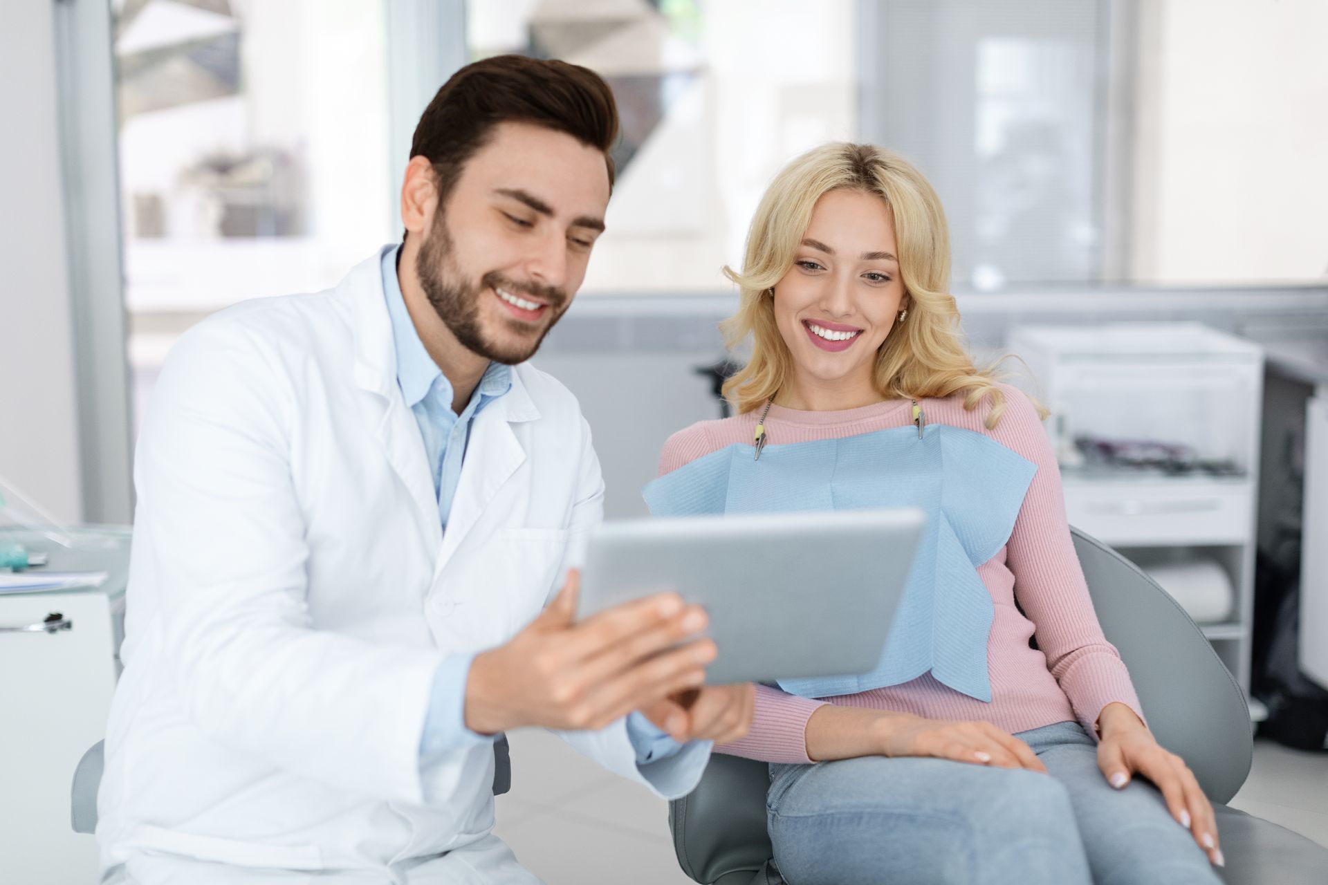 Doctor showing a tablet to a smiling patient in a bright clinic