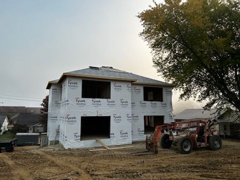 A house is being built with a forklift in front of it.