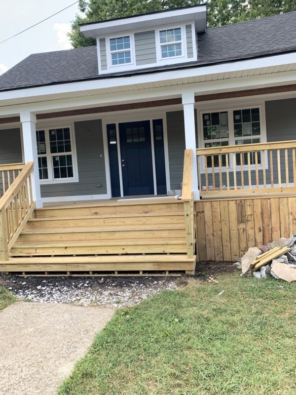 Front porch with wooden ramp and steps on a blue house with white trim and double doors