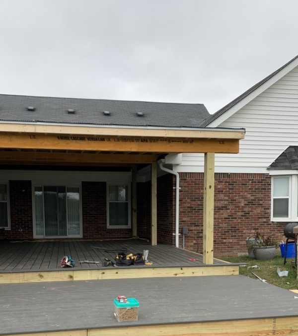 Partially built covered porch with exposed wood framing and brick house exterior