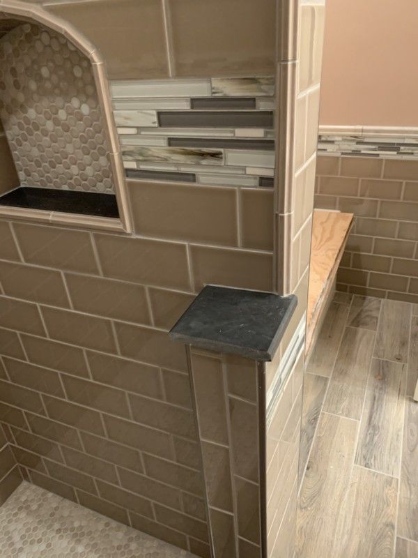Tile-clad pizza oven corner with a small black shelf and wood-look floor