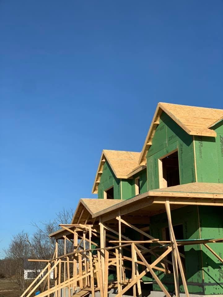 Green house under construction with wooden framing and scaffolding against a blue sky